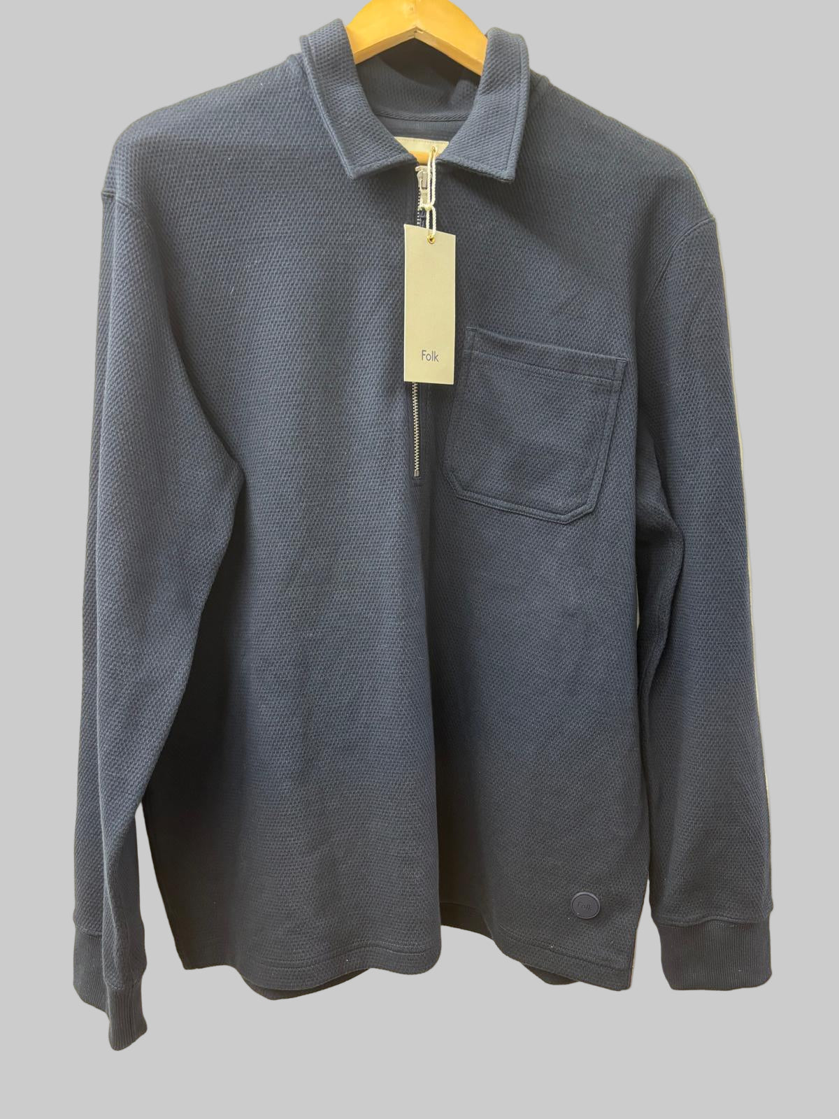 Blue jacket with a tag on a hanger against a beige background