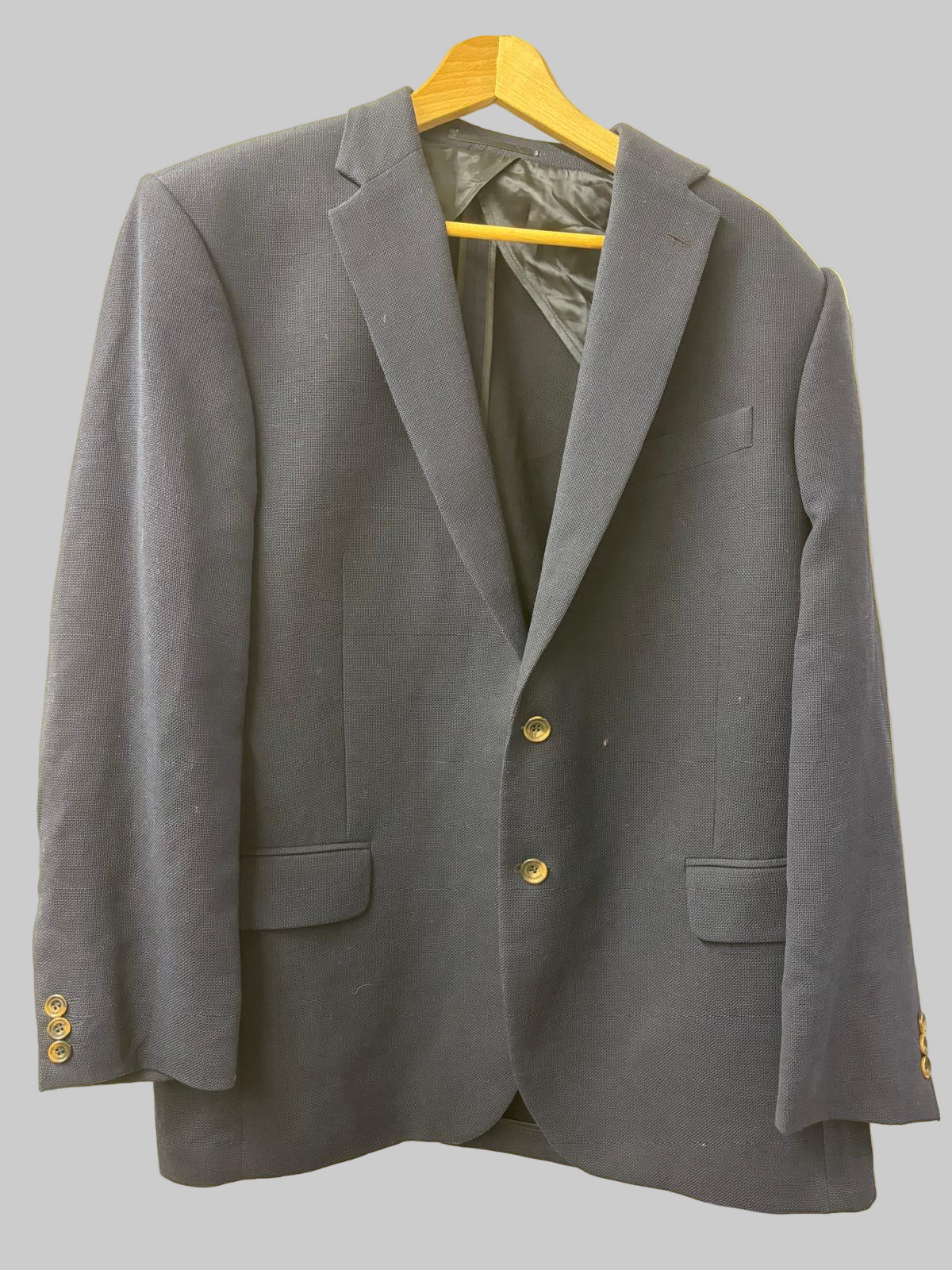 Gray blazer on a yellow hanger against a beige background
